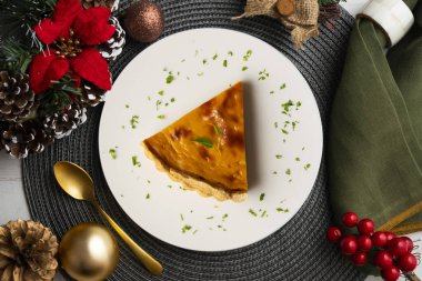 Amerikan balkabağı turtasının leziz bir parçası Noel süslemeleri olan bir masanın üstünde..