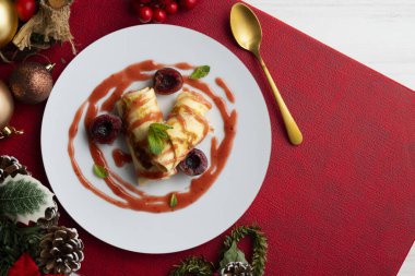 Kiraz soslu krep hamurlu lezzetli börekler. Noel süslemeleri ile süslenmiş masa.