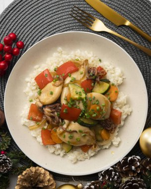 Beyaz pilavın üzerinde sebzeli Wok-Fried Calmare. Noel süsleri olan bir masada yemek..