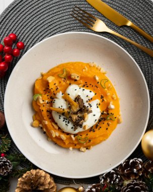 Haşlanmış yumurta ve mantarlı tatlı patates kreması. Noel süslemesi olan bir tabakta..
