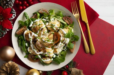 Kızarmış karnabahar salatası ve sebze ve yoğurt sosu. Noel süslemeli bir masada yemek.