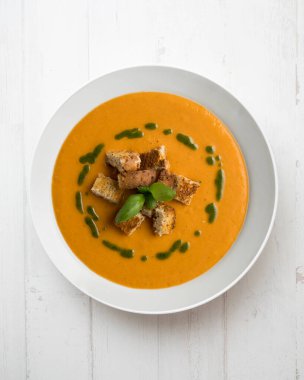 Fesleğen yağı ve kızarmış ekmek ile domates çorbası. Dekorasyonlu üst görünüm tablosu.