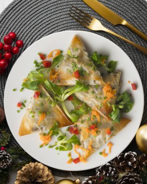 Patlıcan dolu fırınlanmış tuğlalı pasta üçgenleri. Noel süslemeli üst manzara masası.