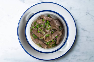 Soğan ve bezelyeyle pişirilmiş sığır eti şeritleri. Dekorasyonlu üst görünüm tablosu.