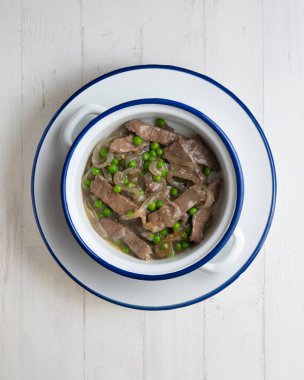 Soğan ve bezelyeyle pişirilmiş sığır eti şeritleri. Dekorasyonlu üst görünüm tablosu.