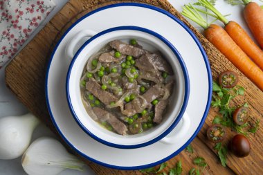 Soğan ve bezelyeyle pişirilmiş sığır eti şeritleri. Dekorasyonlu üst görünüm tablosu.