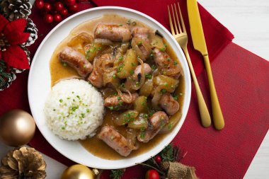 Soğan ve armutla pişirilmiş sosisler. Noel süslemeli üst manzara masası.