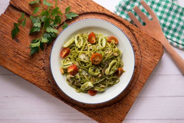 Pesto soslu İtalyan eriştesi ve kalamar. Dekorasyonlu üst görünüm tablosu.