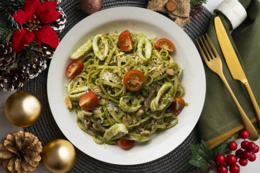 Pesto soslu İtalyan eriştesi ve kalamar. Noel süslemeli üst manzara masası.