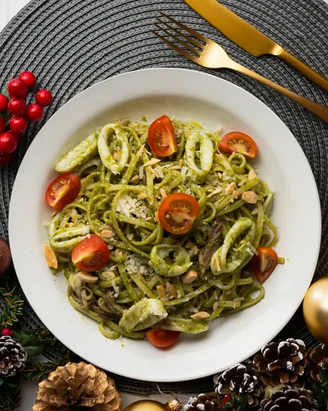 Pesto soslu İtalyan eriştesi ve kalamar. Noel süslemeli üst manzara masası.