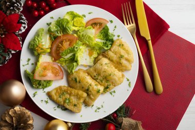 Tempura hake parçaları ve salata. Noel süslemeli üst manzara masası.