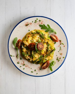 Yeşil kuşkonmaz ve domatesli çırpılmış organik tavuk yumurtası. Dekorasyonlu üst görünüm tablosu.