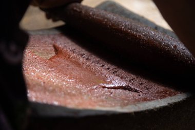 Oaxaca Meksika 'da organik çikolata üreten bir kadın, gıda ürünlerini öğütmek için eski bir taş alet..