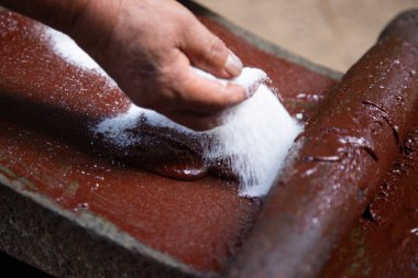Oaxaca Meksika 'da organik çikolata üreten bir kadın, gıda ürünlerini öğütmek için eski bir taş alet..