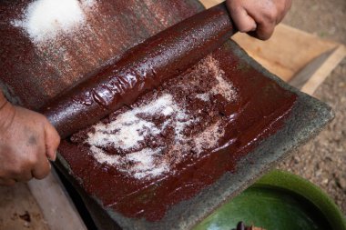 Oaxaca Meksika 'da organik çikolata üreten bir kadın, gıda ürünlerini öğütmek için eski bir taş alet..