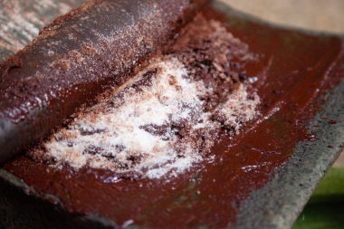 A woman in Oaxaca Mexico manually producing organic chocolate on a metate, an ancient stone tool for grinding food products. clipart