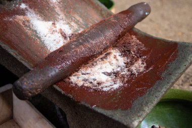 A woman in Oaxaca Mexico manually producing organic chocolate on a metate, an ancient stone tool for grinding food products. clipart