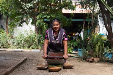 Teotitlan del valle, Oaxaca, Meksika; 1 Kasım 2024: Geleneksel bir aşçı, malzemeleri öğütmek için antik bir mutfak gereci olan metaya çikolata öğüttü.