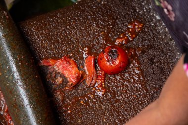 Woman from an indigenous community in Oaxaca preparing traditional Mole Rojo with a metate, a tool for grinding ingredients in Mexico. clipart