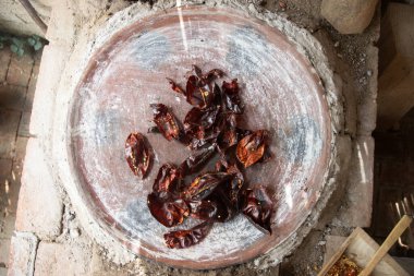 Preparing Mexican Mole Negro. Oaxaca chiles have to be cleaned, toasted on a comal over a flame and soaked in water before grinding with metate. clipart