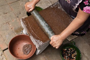 Meksikalı Köstebek Zencisi hazırlanıyor. Oaxaca chiles temizlenmeli, bir alevin üzerinde kızartılmalı ve metayla öğütülmeden önce suya batırılmalı..