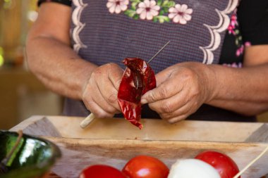 Meksikalı Köstebek Zencisi hazırlanıyor. Oaxaca chiles temizlenmeli, bir alevin üzerinde kızartılmalı ve metayla öğütülmeden önce suya batırılmalı..