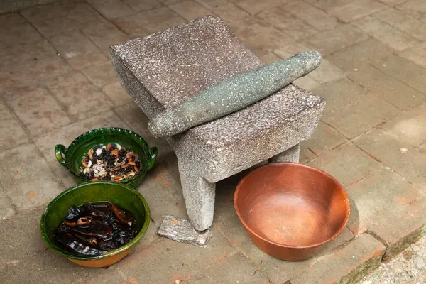 Oaxaca 'daki yerli bir toplumdan bir kadın, Meksika' daki malzemeleri öğütmek için kullanılan bir aletle geleneksel siyah köstebeği hazırlıyor..