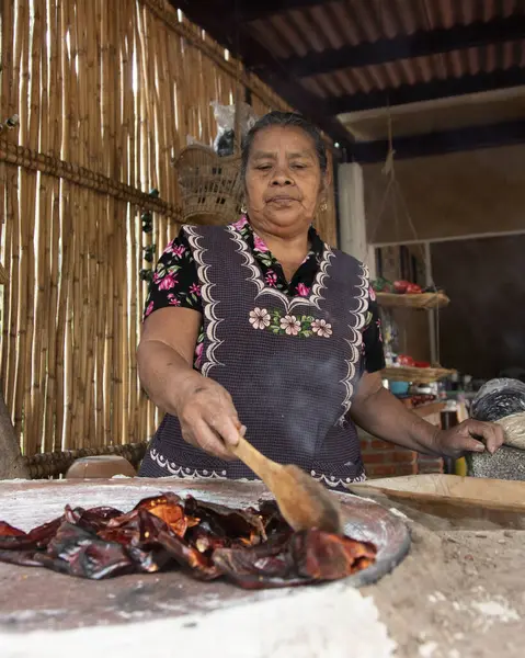 Teotitlan del valle, Oaxaca, Meksika 1 Kasım 2024: Geleneksel bir Oaxacan aşçısı bir metate üzerinde siyah köstebek hazırlıyor. 