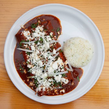 Geleneksel enchilada, Oaxaca peyniri, kırmızı et ve pilav. Enchilada, Meksika mutfağından sarılmış veya katlanmış mısır tortillasıyla yapılan bir yemektir..