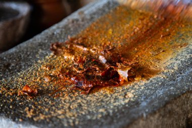 Woman from an indigenous community in Oaxaca preparing traditional red mole with a metate, a tool for grinding ingredients in Mexico. clipart