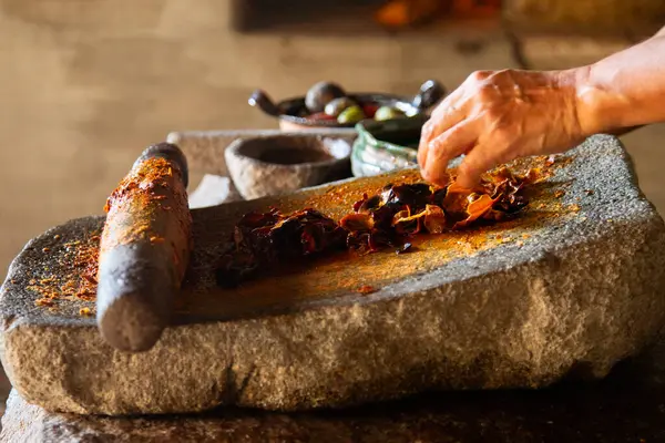 Oaxaca 'daki yerli bir topluluktan bir kadın, Meksika' daki malzemeleri öğütmek için kullanılan bir meta ile geleneksel kırmızı köstebeği hazırlıyor..