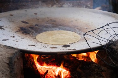 Meksika Oaxaca 'da bir açık ateş mutfağında geleneksel bir Comal üzerinde el yapımı mısır tortillası pişirmek..