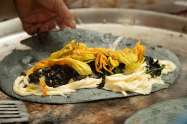 Kabak çiçeği, huitlacoche ve peynirli quesadilla. Meksika, Puebla 'daki Cholula pazarında geleneksel bir komal üzerinde mor mısırla yapılır..