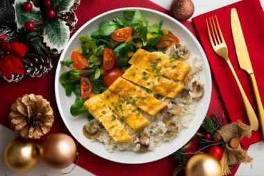Peynir, pirinç ve salata ile dolu bir omlet ile tabak. Noel süslemeleri ile en üstteki görünüm masası.