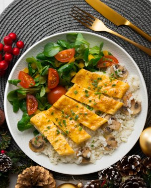 Peynir, pirinç ve salata ile dolu bir omlet ile tabak. Noel süslemeleri ile en üstteki görünüm masası.
