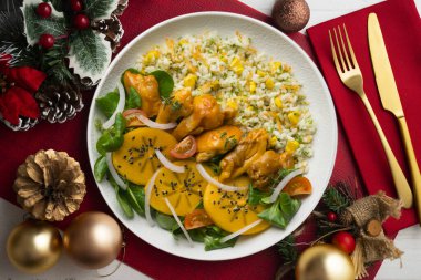 Tavuk, hurma salatası ve pilavla kombinasyon tabağı. Noel süslemeleri ile en üstteki görünüm masası.