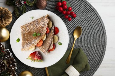 Çilek ve taze muzla dolu çikolatalı krepler. Noel süslemeleri ile en üstteki görünüm masası.