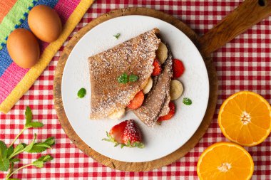 Çilek ve taze muzla dolu çikolatalı krepler. Noel süslemeleri ile en üstteki görünüm masası.