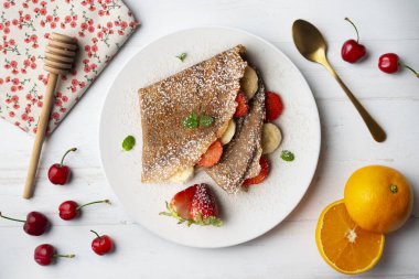 Çilek ve taze muzla dolu çikolatalı krepler. Noel süslemeleri ile en üstteki görünüm masası.