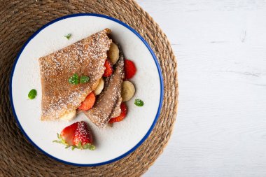 Çilek ve taze muzla dolu çikolatalı krepler. Noel süslemeleri ile en üstteki görünüm masası.