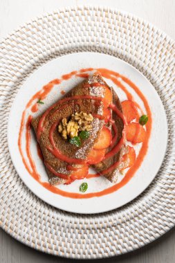 Çilek ve meyve sosuyla dolu çikolatalı krepler. Noel süslemeleri ile en üstteki görünüm masası.