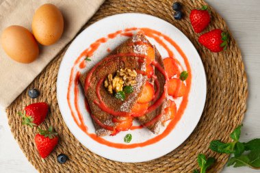 Çilek ve meyve sosuyla dolu çikolatalı krepler. Noel süslemeleri ile en üstteki görünüm masası.