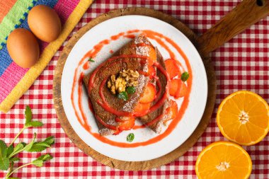 Çilek ve meyve sosuyla dolu çikolatalı krepler. Noel süslemeleri ile en üstteki görünüm masası.