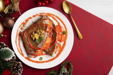 Çilek ve meyve sosuyla dolu çikolatalı krepler. Noel süslemeleri ile en üstteki görünüm masası.