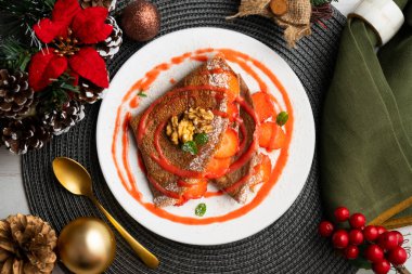 Çilek ve meyve sosuyla dolu çikolatalı krepler. Noel süslemeleri ile en üstteki görünüm masası.