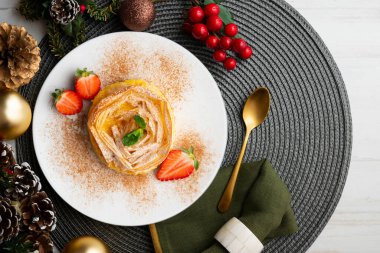 Kremayla doldurulmuş filo pastasından yapılmış çiçek şeklinde tart. Noel süslemeleri ile en üstteki görünüm masası.