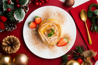 Kremayla doldurulmuş filo pastasından yapılmış çiçek şeklinde tart. Noel süslemeleri ile en üstteki görünüm masası.
