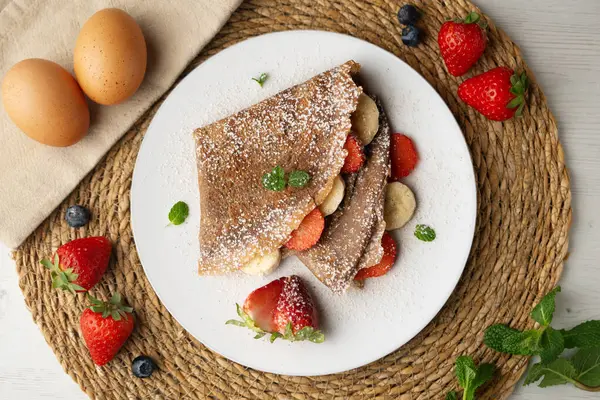 Çilek ve taze muzla dolu çikolatalı krepler. Noel süslemeleri ile en üstteki görünüm masası.