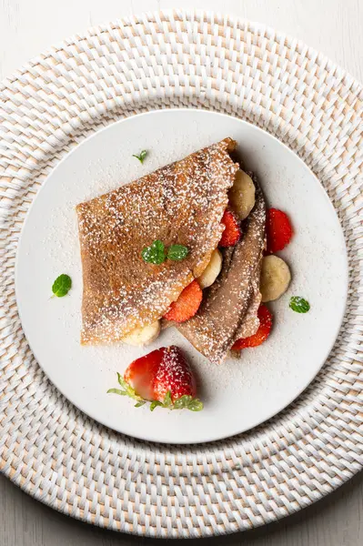 Çilek ve taze muzla dolu çikolatalı krepler. Noel süslemeleri ile en üstteki görünüm masası.