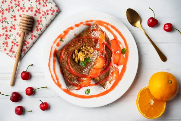 Çilek ve meyve sosuyla dolu çikolatalı krepler. Noel süslemeleri ile en üstteki görünüm masası.